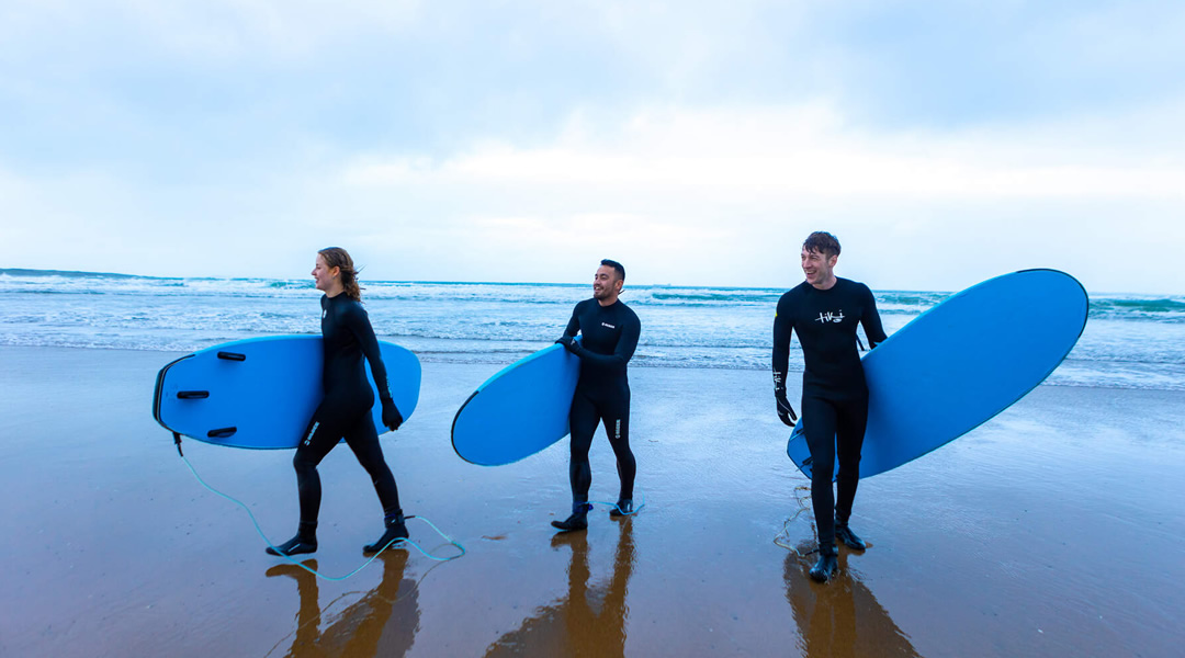 3 surfers with boards on beach at Strandhill, Sligo